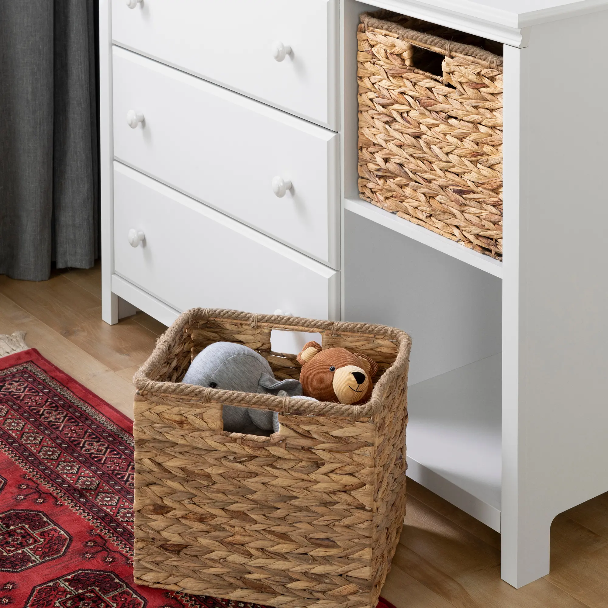 Side view of dresser with drawers and woven basket in cubby, children’s toys shelf visible.