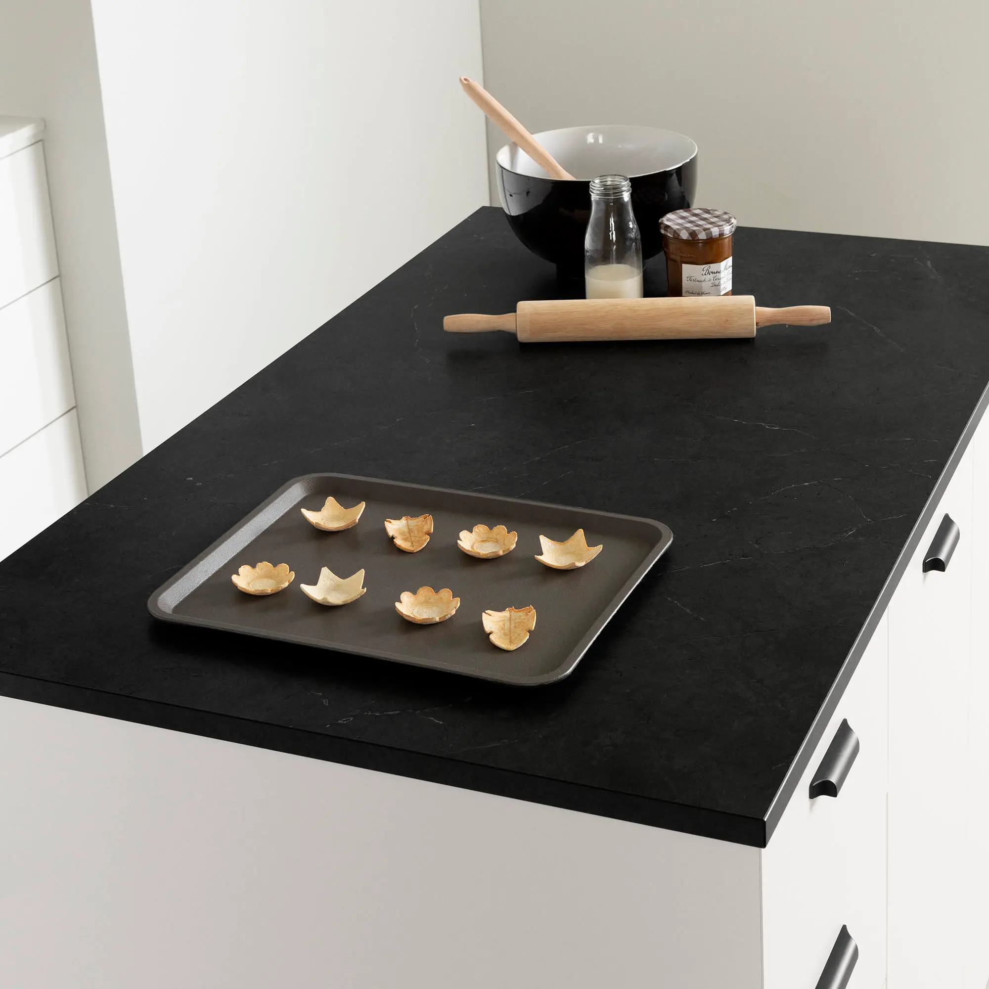 Close-up of black countertop edge over white cabinet with seam details.