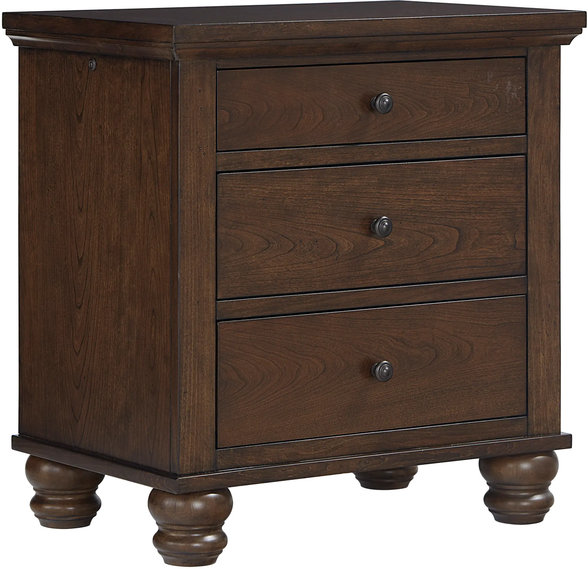 A dark wood bedside table with three drawers and turned feet beside a bed, with a lamp, vase of flowers, books, and a charging cable on top.